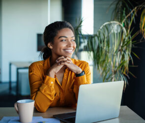 Small business owner smiling while working on a laptop, representing a positive client experience