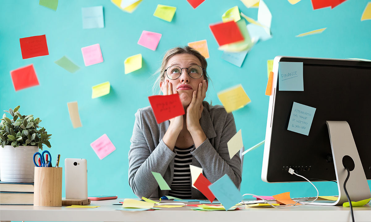 Overwhelmed business owner resting her chin in her hands at a desk surrounded by scattered sticky notes