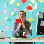 Overwhelmed business owner resting her chin in her hands at a desk surrounded by scattered sticky notes