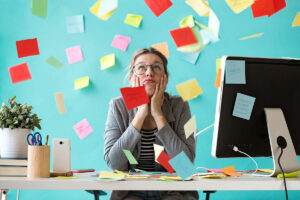 Overwhelmed business owner resting her chin in her hands at a desk surrounded by scattered sticky notes