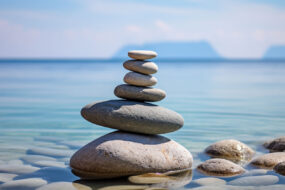Stack of balanced smooth stones in calm shallow water, representing work-life balance for small business owners