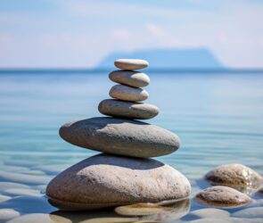 Stack of balanced smooth stones in calm shallow water, representing work-life balance for small business owners