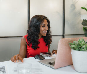 Consultant working at a laptop at a white desk with client paperwork spread beside her