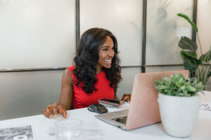 Consultant working at a laptop at a white desk with client paperwork spread beside her